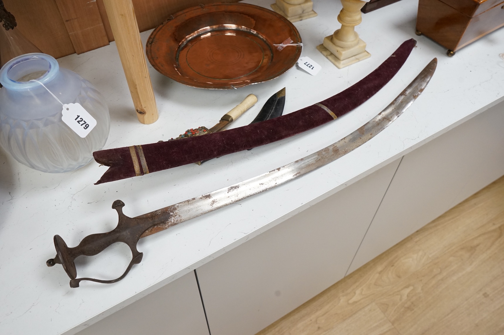 An Indian Tulwar sword, in scabbard and two small kukri, largest 93cm long.